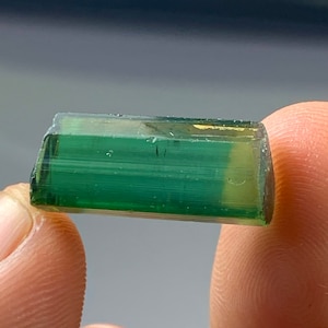 May include: A green and yellow gemstone with striations, a type of tourmaline.