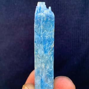 Op de afbeelding: Een lichtblauw aquamarijn kristal met een puntige punt en een ruw, getextureerd oppervlak.
