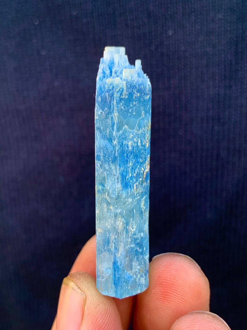 Op de afbeelding: Een lichtblauw aquamarijn kristal met een puntige punt en een ruw, getextureerd oppervlak.