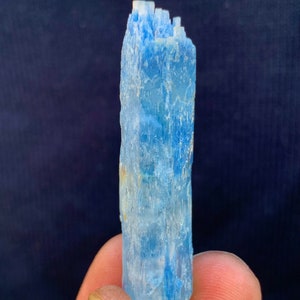 Op de afbeelding: Een lichtblauw aquamarijn kristal met een puntige punt en een ruw, getextureerd oppervlak.