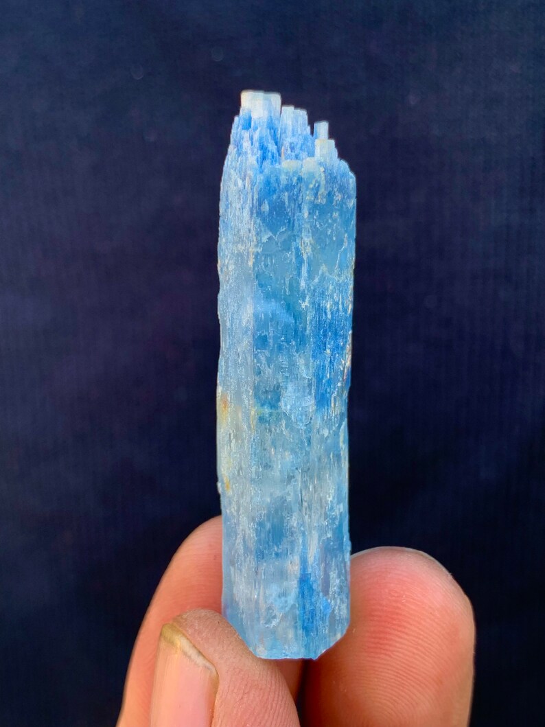 Op de afbeelding: Een lichtblauw aquamarijn kristal met een puntige punt en een ruw, getextureerd oppervlak.