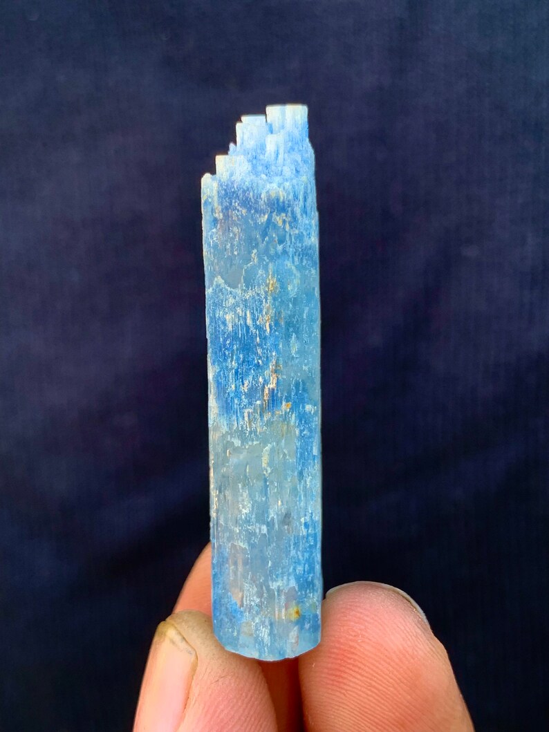 Op de afbeelding: Een lichtblauw aquamarijnkristal met een gestreepte textuur. Het kristal is ongeveer 7,5 cm lang en heeft een licht puntige punt.