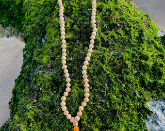 May include: A wooden mala bead necklace with a bright orange tassel. The necklace is made of natural wood beads and is strung on a thin cord. The tassel is made of a soft, silky fabric.