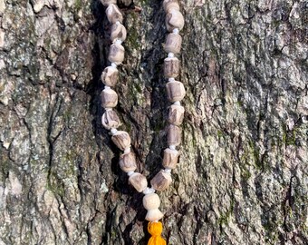 May include: A wooden beaded necklace with a tassel. The beads are a light brown colour and the tassel is a bright yellow.