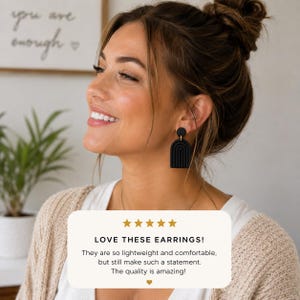 K&ouml;nnte beinhalten: Mattschwarze H&auml;ngeohrringe mit einem gestuften Bogendesign und einem kleinen runden Stecker. Die Ohrringe werden an einer Person gezeigt und von einer Bewertung begleitet, die lautet: LOVE THESE EARRINGS! They are so lightweight and comfortable, but still make such a statement. The quality is amazing!