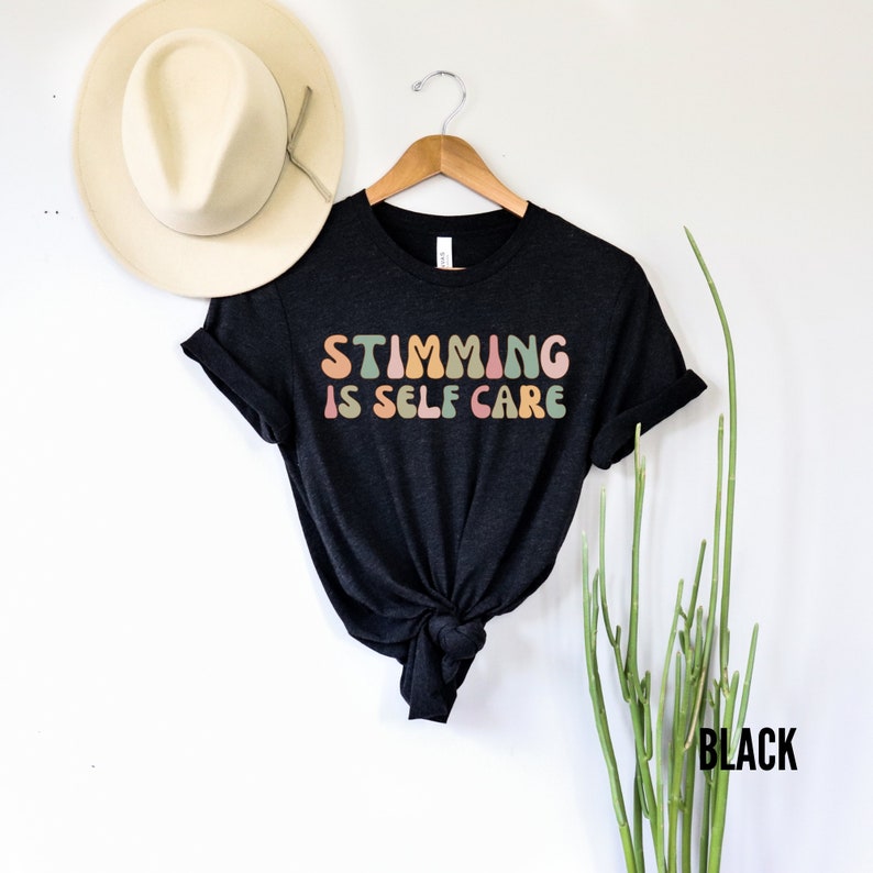 May include: Black t-shirt with the text "Stimming is Self Care" in rainbow coloured letters.