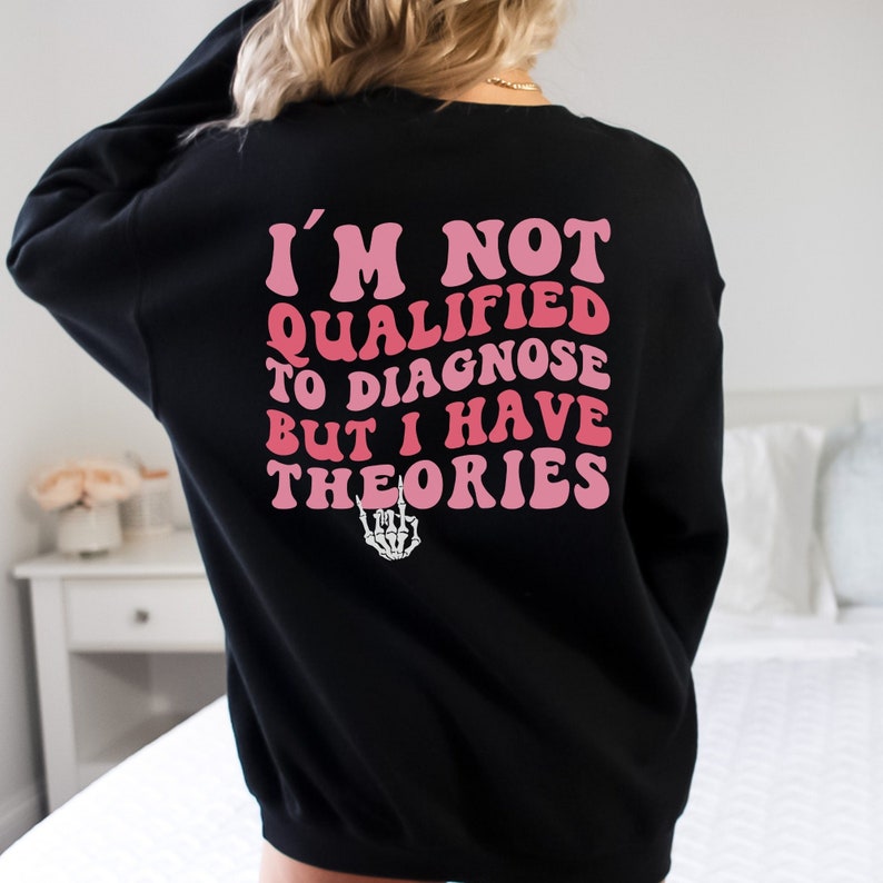 May include: Black sweatshirt with a pink graphic that says "I'm not qualified to diagnose but I have theories" with a skeleton hand giving the rock and roll sign.