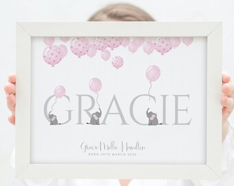 May include: A framed print with a pink and gray color scheme. The print features the name "GRACIE" in large gray letters with three small gray elephants holding pink balloons. The text "Gracie Millie Hamilton Born 24th March 2020" is printed below the name.