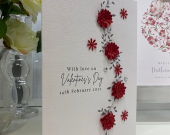 May include: A white card with a red floral design and the text "With love on Valentine's Day 14th February 2022".