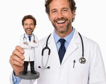 May include: A smiling man in a white lab coat and a stethoscope holds a small figurine of a doctor. The figurine is wearing a white coat, black pants, and a stethoscope. The background is white.