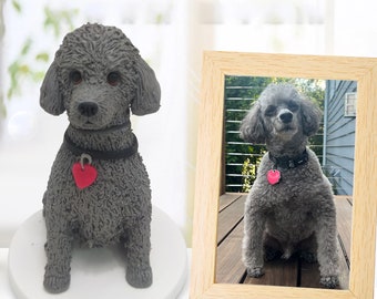 May include: A gray poodle figurine with a black collar and a red heart tag. The figurine is sitting on a white base with the name "Pluto" written on it. A framed photo of a gray poodle is in the background.