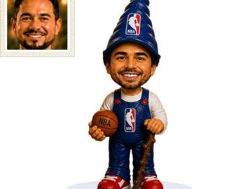 May include: A custom bobblehead figurine featuring a smiling man with a beard, wearing blue overalls with an NBA logo and a matching blue spiral gnome hat with an NBA logo. The figure holds a brown basketball and stands on a white circular base.