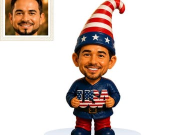 May include: A custom bobblehead figurine featuring a person with a beard wearing a blue shirt and red pants. The figure wears a tall hat with red and white stripes and white stars. The figure holds a sign with the letters USA in a flag pattern.