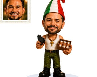 May include: A custom bobblehead figure featuring a man with a beard wearing a white tank top, green pants, black boots, and a gold cross necklace. The figure wears a tall hat with green, white, and red stripes, holds a black handgun, and carries a box of cannoli.