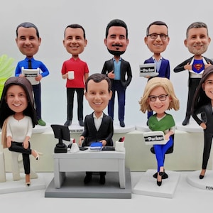 May include: A set of ten custom bobbleheads, each with a unique personality and expression. The bobbleheads are dressed in various outfits, including a blue shirt and tie, a red polo shirt, a black suit, a blue suit, a green shirt, a black suit, a black dress, and a blue shirt with a Superman logo. The bobbleheads are standing on individual bases, some with a desk and computer, and some with a laptop. The bobbleheads are a fun and unique way to personalize your home or office.