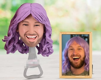 May include: A custom bottle opener with a 3D sculpted head wearing a purple wig. The head is smiling and the bottle opener is made of metal. A framed photo of the same head is in the background.