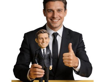 May include: A bobblehead doll of a man in a black suit, white shirt, and black tie. The doll is held by a man in a matching suit, who gives a thumbs-up. The background is white.