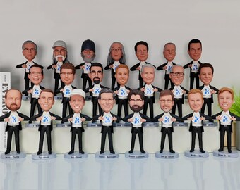 May include: A group of 18 custom bobbleheads, each wearing a black suit and holding a white and blue logo in front of their chest. The bobbleheads are arranged in three rows on a white surface.