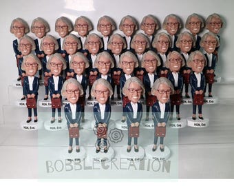 May include: A group of 25 bobbleheads of a person wearing a blue suit and holding a briefcase. The bobbleheads are arranged in rows on a white shelf. The bobbleheads are all identical except for the text on the base, which reads "HGN, Esq."