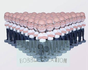 May include: A group of 25 custom bobbleheads, all wearing white shirts and blue pants, with a variety of facial expressions. The bobbleheads are arranged in a semi-circle, with the text "BOBBLECRETATION" at the bottom of the image.