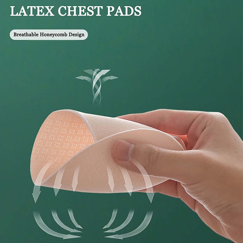 May include: A close-up of a pair of pink latex chest pads with a honeycomb design. The pads are being held in a hand and arrows indicate the breathability of the material.