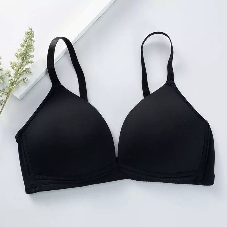 May include: A black wireless bra with adjustable straps. The bra has a smooth, seamless design and a plunging neckline.