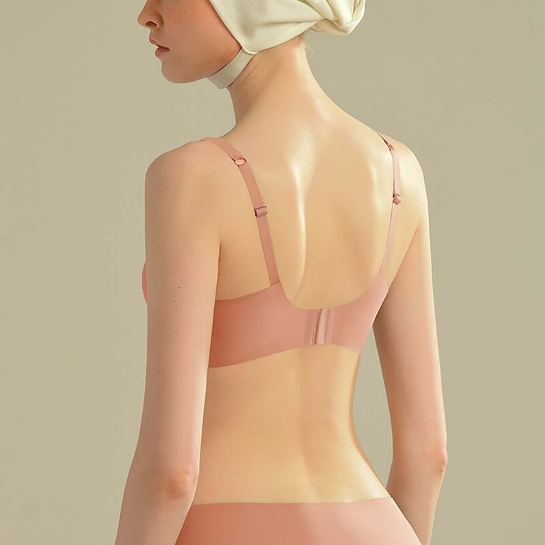 May include: A nude-colored seamless bra with adjustable straps. The bra is made of a soft, stretchy material and has a smooth, seamless finish.