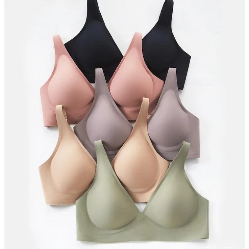 May include: A stack of six seamless bras in various colors, including black, pink, beige, gray, and green. The bras are made of a soft, stretchy material and have a smooth, seamless design.