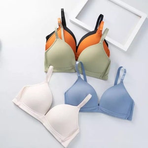 May include: Four bras in different colors: green, orange, white, and blue. The bras are made of a soft, smooth fabric and have adjustable straps.