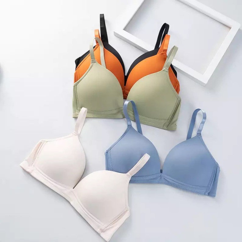 May include: Four bras in different colors: green, orange, white, and blue. The bras are made of a soft, smooth fabric and have adjustable straps.