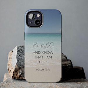 May include: A phone case with a beach scene and the text "Be still. And know that I am God. Psalm 46:10".