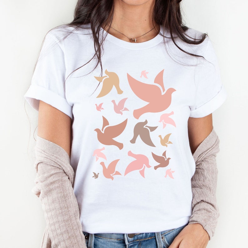 May include: White t-shirt with a pattern of pink and brown stylized doves.
