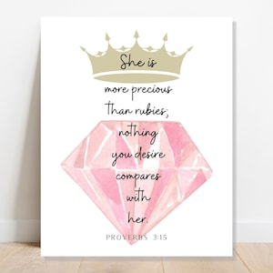 May include: A pink diamond with a gold crown above it. The text reads "She is more precious than rubies; nothing you desire compares with her. PROVERBS 3:15"