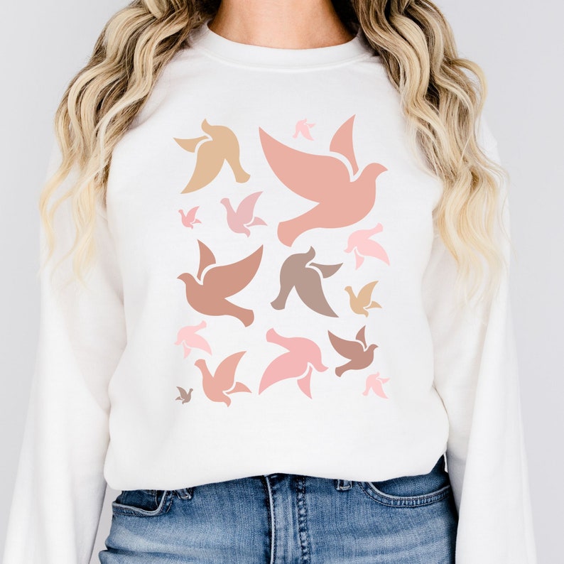 May include: White sweatshirt with a pattern of pink, peach, and brown doves. The doves are all facing the same direction and are arranged in a random pattern.