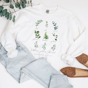 May include: White sweatshirt with a green leafy design and the text "love, joy, peace, patience, kindness, goodness, faithfulness, gentleness, self-control, GALATIANS 5:22-23".