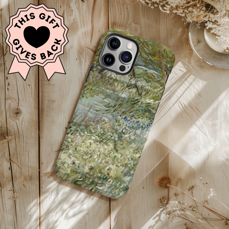 Peut inclure: Coque de t&eacute;l&eacute;phone orn&eacute;e d'une peinture impressionniste de paysage aux tons verts et bleus. Le bo&icirc;tier a un bord noir et une finition brillante. Un badge rose avec le texte "THIS GIFT GIVES BACK" et un c&oelig;ur noir est visible.