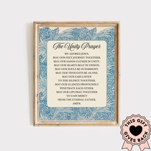 May include: Framed print featuring "The Unity Prayer" in elegant script. The text is centered on a cream-colored background, framed by a blue floral design. The frame is a light wood color. A pink ribbon with the text "This Gift Gives Back" is in the bottom right corner.