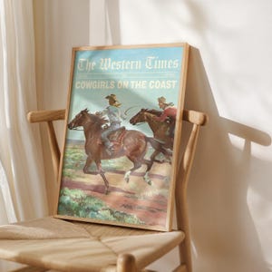 May include: A framed print titled "The Western Times" featuring a vintage illustration of cowgirls riding horses. The artwork depicts two cowgirls on horseback, with the text "Cowgirls on the Coast" below the title. The print is displayed on a wooden chair.
