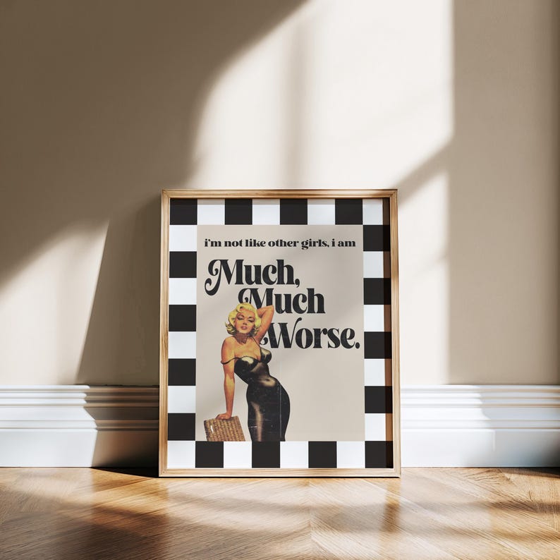 May include: Framed art print featuring a vintage-style image of a woman in a black dress with the text "Much, Much Worse." The print has a black and white checkered border and a wooden frame. The woman is blonde and is leaning on a woven basket.
