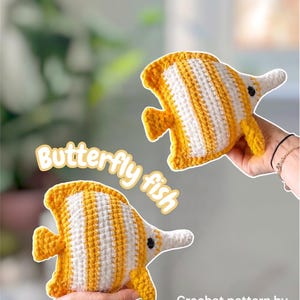 May include: Two handmade crochet butterfly fish in yellow and white. The fish have a distinctive shape with a long snout and a striped pattern. The text "Butterfly fish" is displayed in a playful font. The text "Crochet pattern by @blue.beena" is also visible.