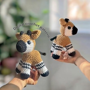 May include: Two crocheted giraffe toys. The giraffes are brown, black, and white. The text "Digital crochet pattern" is in the upper left corner. The toys are held in hands.