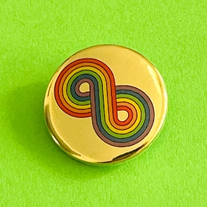 May include: A circular, gold-toned badge with a retro rainbow design. The design features curved lines in red, orange, yellow, green, blue, and purple. The badge is set against a bright green background.