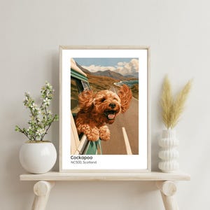 May include: A framed art print featuring a brown Cockapoo dog with its head out of a vehicle window, ears blowing in the wind, against a backdrop of the Scottish NC500 landscape. The text below the image reads Cockapoo NC500, Scotland.