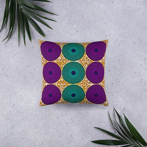 May include: Square cushion with a striking pattern. It displays large, circular designs in purple and teal, set on a background of small, gold and white dots. This is a decorative item for the home.