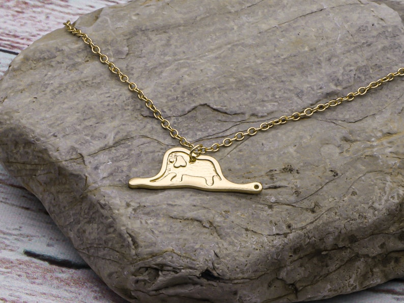 May include: A gold necklace with a pendant shaped like the 'The Giving Tree' illustration. The pendant features a tree with a trunk and branches, and a person sitting on the trunk.