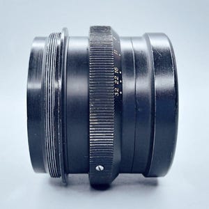 May include: A black camera lens with a silver aperture ring and markings that read "32 22 16".