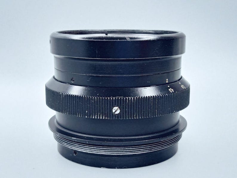 May include: A black camera lens with a series of rings and a screw on the side.