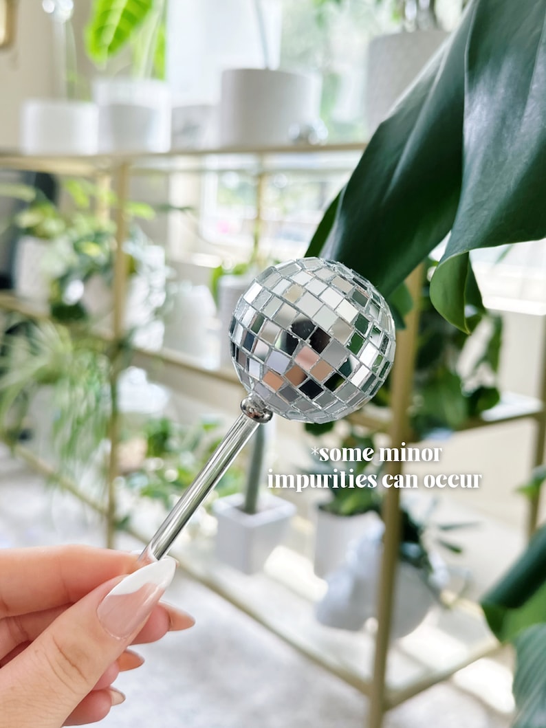 May include: A silver disco ball on a clear glass stick. The disco ball is made up of many small mirrored squares. *some minor impurities can occur*