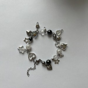 May include: A silver charm bracelet featuring black and clear beads, silver stars, and heart charms.