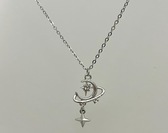 May include: A silver necklace with a crescent moon and star charm. The moon charm has a small crystal in the center and the star charm hangs from the bottom of the moon.